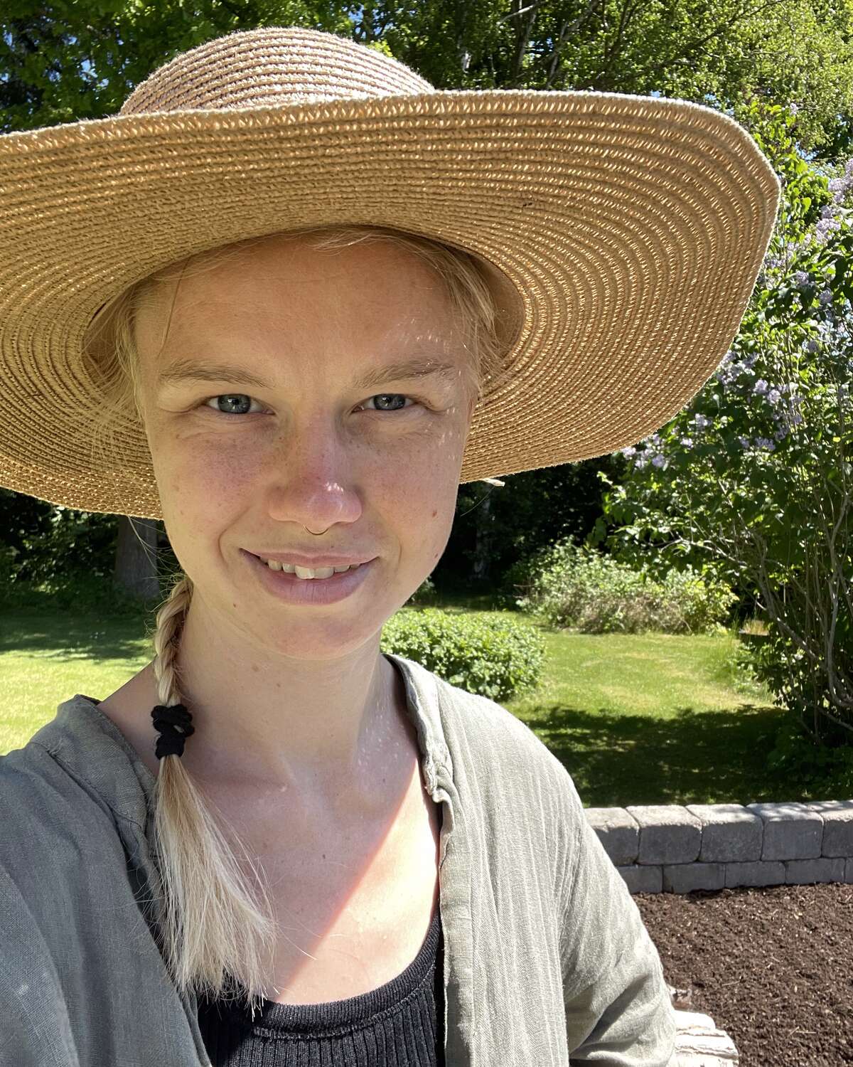Laura med solhat ved frodig køkkenhave